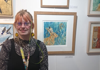 Manager, Lauren McQuaid in front of the animal-themed exhibition