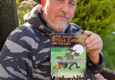 Author Julian Noyce, with a paperback copy of this book More adventures of Stella Earwax and Friends