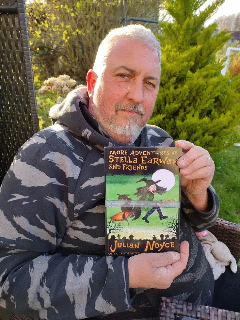 Author Julian Noyce, with a paperback copy of this book More adventures of Stella Earwax and Friends